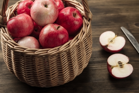Basket of fresh ripe red apples on wooden backgroundの写真素材