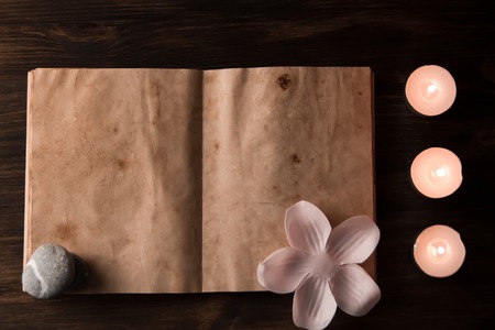 Beautiful Spa composition with aroma candles and empty vintage open book on wooden backgroundの写真素材