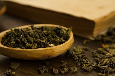 Oolong tea in wooden spoon on a background of old vintage booksの写真素材