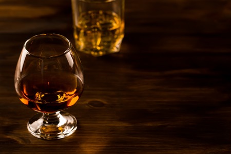 glass of whiskey with ice on a wooden tableの写真素材