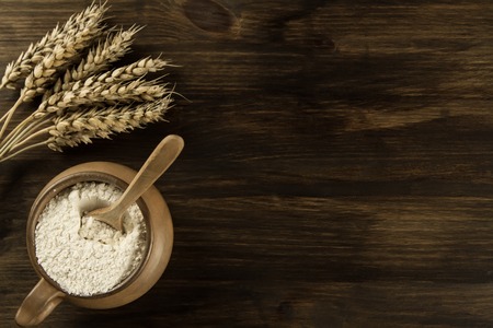 pot of flour and wheat ears on wooden backgroundの写真素材