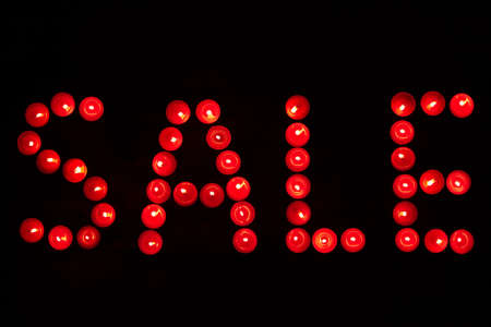 The word sale written with candles on a dark background