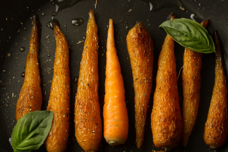 whole roasted carrots with spices in a skilletの写真素材