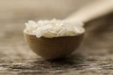 Long grain rice in a wooden spoon on the table. Healthy eating, diet, vegetarianism.の写真素材