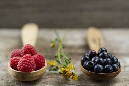 Raspberries and blueberries in spoons on wooden background. Healthy eating and dietの写真素材