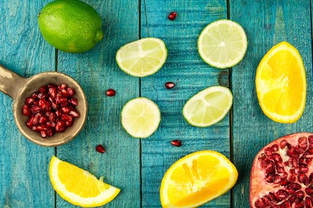 Ripe lime, orange, pomegranate fruit on wooden vintage background. Healthy vegetarian food. Recipe, menu, mock up, cooking.の写真素材