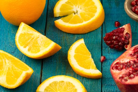 Ripe lime, orange, pomegranate fruit on wooden vintage background. Healthy vegetarian food. Recipe, menu, mock up, cooking.の写真素材