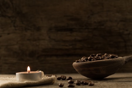 fragrant fried coffee beans. light  burning brightly candles on old wooden background.の写真素材