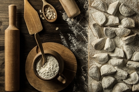 homemade pasta ravioli over wooden table with flour. kitchen utensilsの写真素材
