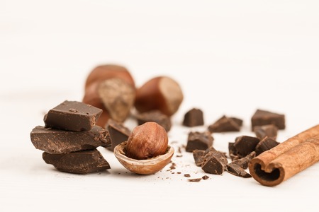Broken chocolate bar, hazelnut and cinnamon on wooden background, close-upの写真素材