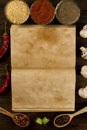 open old vintage book with spices on wooden background. Healthy vegetarian food. Recipe, menu, mock up, cooking.の写真素材