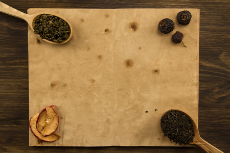 black, Oolong in a spoon, dried apples on the old blank open book on wooden background. Menu, recipe, mock upの写真素材
