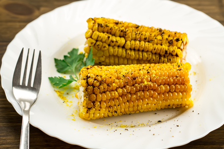 roasted corn on a white plate with spices on wooden background. Healthy vegetarian food.の写真素材