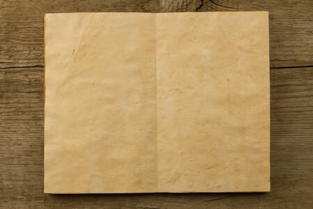 open old vintage book on the aged wooden background. Two clean sheet of paper.の写真素材