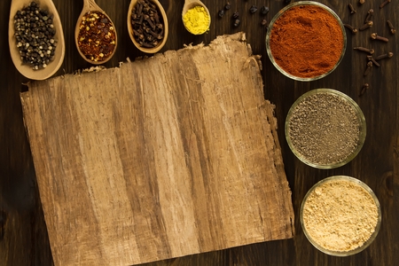 sheet old vintage paper with spices on wooden background. Healthy vegetarian food. Recipe, menu, mock up, cooking.の写真素材