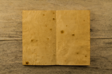 open old vintage book on the aged wooden background. Two clean sheet of paper.の写真素材