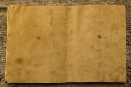 open old vintage book on the aged wooden background. Two clean sheet of paper.の写真素材