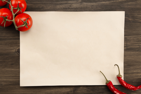 sheet old vintage paper with tomatoes and Chile peppers aged wooden background. Healthy vegetarian food. Recipe, menu, mock up, cooking.の写真素材