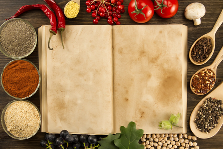 open old vintage book with spices on wooden background. Healthy vegetarian food. Recipe, menu, mock up, cooking.の写真素材