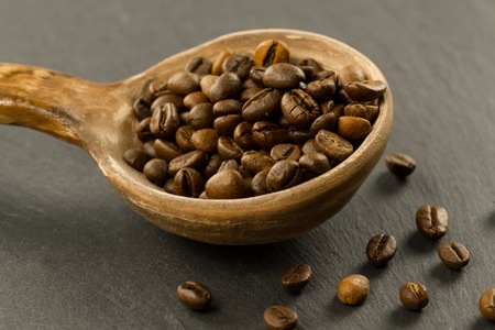 fragrant coffee beans in a spoon on a black backgroundの写真素材