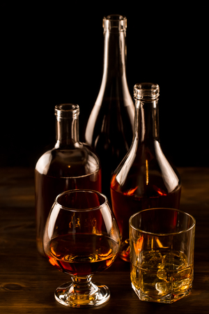 glass of whiskey with ice and a bottle on a wooden table. Cognac, brandy.の写真素材