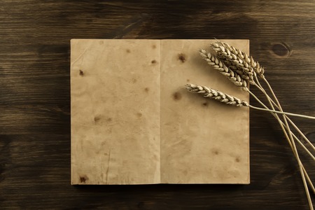 open old vintage book on the aged wooden background. ears of wheat. homemade, menu, recipe, mock upの写真素材