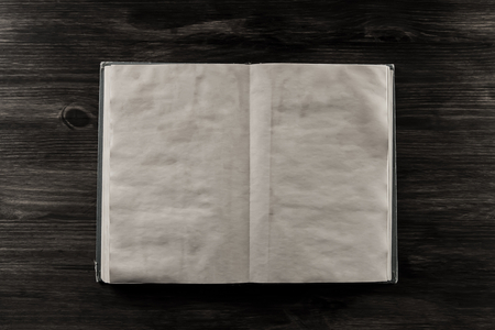 open old vintage book on the aged wooden background. Two clean sheet of paper.の写真素材