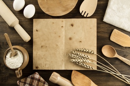 open old vintage book on the aged wooden background. Kitchen utensils, ears of wheat, flour in a pot. homemade, menu, recipe, mock upの写真素材