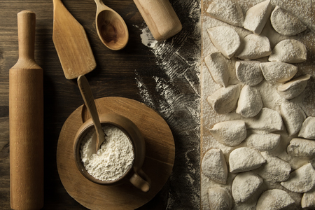 homemade pasta ravioli over wooden table with flour. kitchen utensilsの写真素材