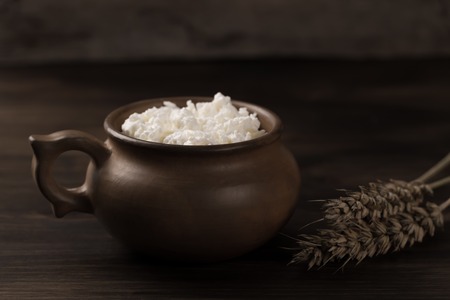 fresh tasty curd in pot on wooden background. Homemade, cottage cheeseの写真素材