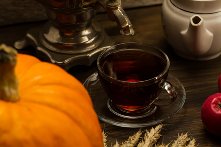Tea still life with samovar, apples, ripe orange pumpkins, maple leaves, wheat on wooden background. Thanksgiving, autumn.の写真素材