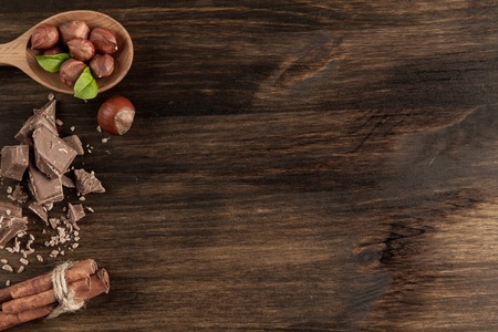 Broken chocolate bar, hazelnut and cinnamon on wooden background, close-upの写真素材