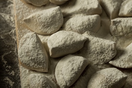 homemade pasta ravioli over wooden table with flour. kitchen utensilsの写真素材