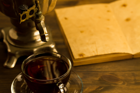 Tea still life with samovar on wooden background. Empty open an old vintage book. Russia autumn.の写真素材