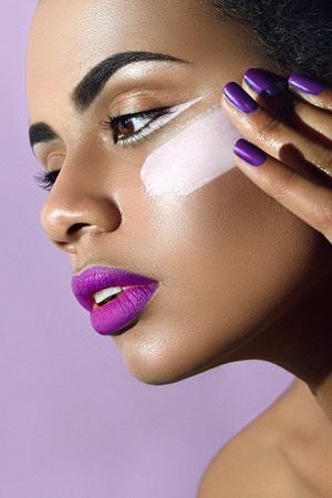 Mulatto with purple lipstick and purple nails and white paint smear on the cheek.の写真素材