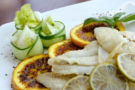 Fish served with grilled slices of orangeの写真素材