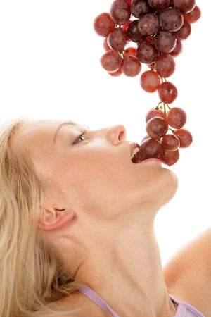 Portrait of young blonde woman eating red grapesの写真素材