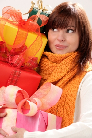 Portrait of young surprised woman holding pile of giftsの写真素材