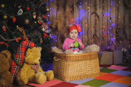 Children in a basket near New year tree. Little girl near New year tree in studio.の写真素材