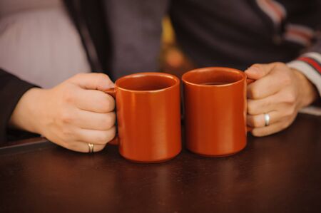 The two clubs are on a wooden table in the hands of the couple. Warming tea. Family conversation...