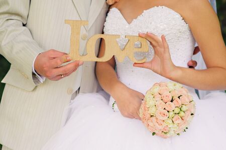 Love - wooden inscription for wedding in the hands of the bride and groom. Wedding decor.の写真素材