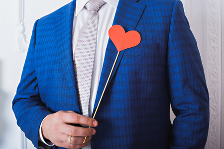 Red heart on a stick in a man's hands. a man in a blue jacket. Gorizontal.の写真素材