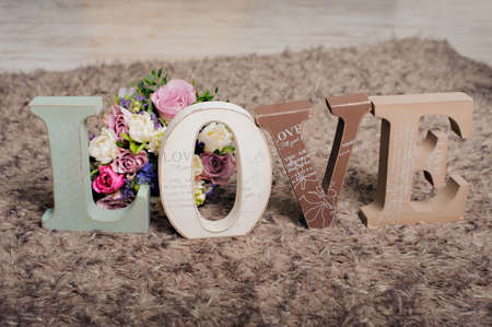 Vintage wooden inscription Love with beautiful bouquet of flowers on the brown background.の写真素材