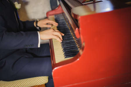 close up of male hands playing red piano. Horizontal shape, copy spaceの写真素材