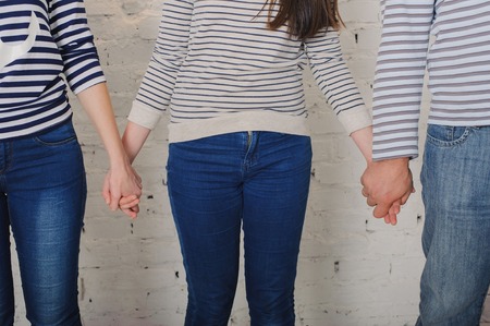 Family mom dad and daughter hold hands all. Dressed in jeans and striped sweaters. Love. Horizontalの写真素材