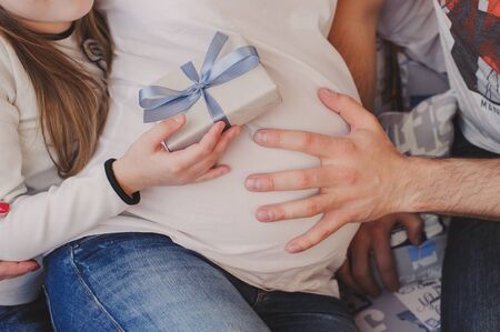Husband and child hugging a pregnant woman's belly. In the hands of a child's gift. The concept of a...