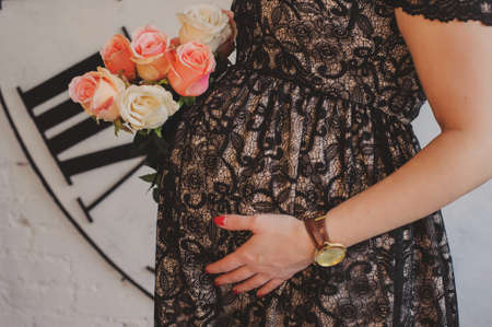 Pregnant woman in dress hugs her belly. A woman waiting for a child.