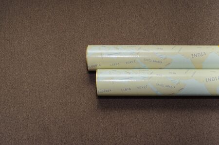 Two folded maps of the world on the brown background. scratch map of world, space place for text. Travel concept.の写真素材