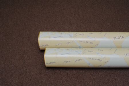 Two folded maps of the world on the brown background. scratch map of world, space place for text. Travel concept.の写真素材
