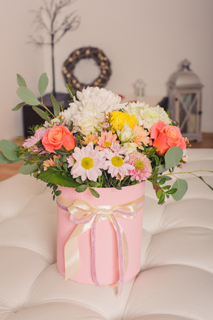 Mixed bouquet of various flowers in a hat box in modern interior vertical photoの写真素材